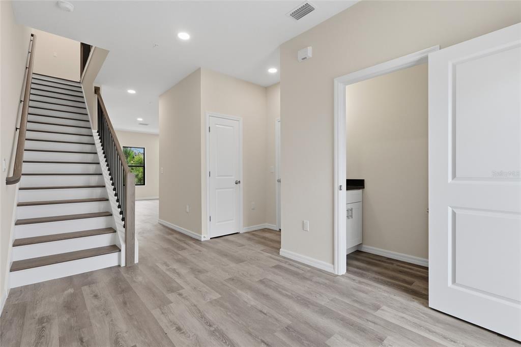 A staircase with dark wood treads and a metal railing sits beside a hallway — 4369 CAMBIO GARDENS COURT, TAMPA, FL