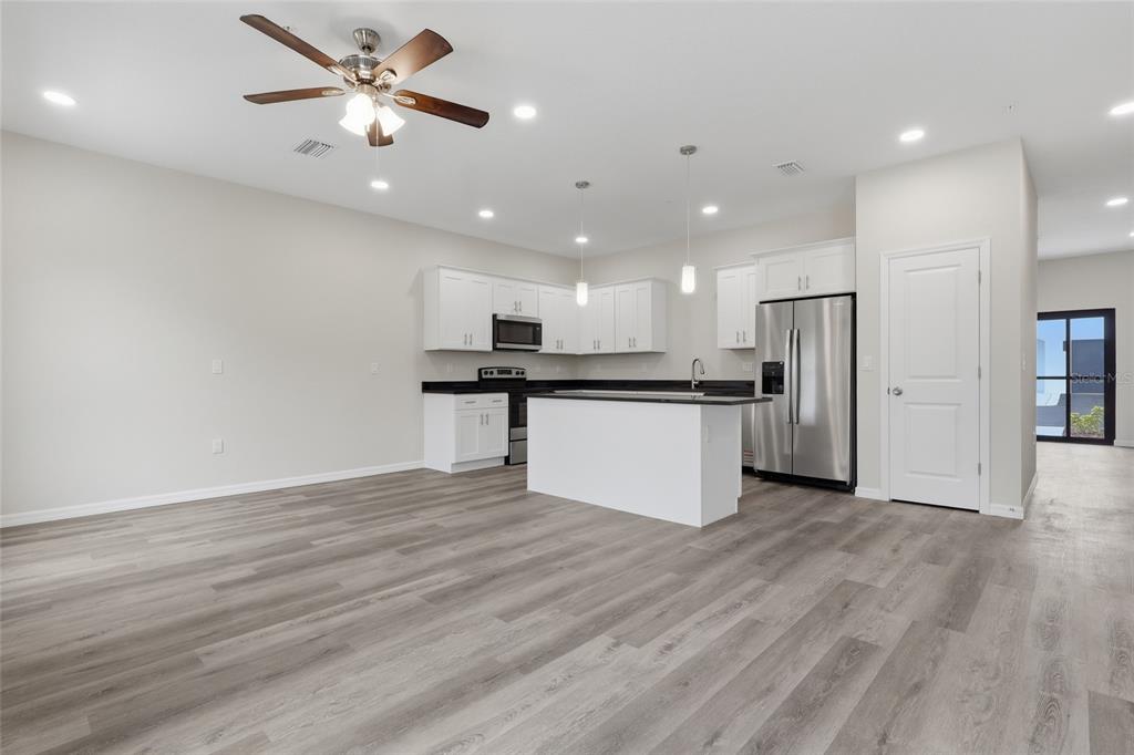 A kitchen with white cabinets, a central island, and stainless steel appliances over wood flooring — 4369 CAMBIO GARDENS COURT, TAMPA, FL