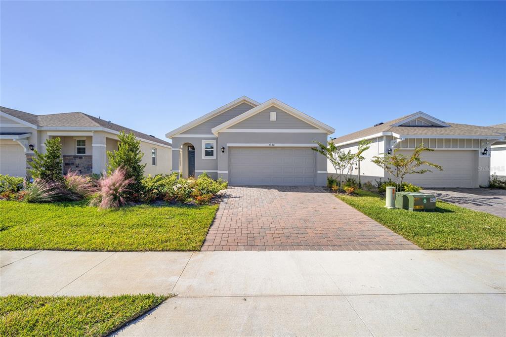 A single-story house with a gray exterior, a two-car garage, and a brick paver driveway — 5430 NW 46TH LANE ROAD, OCALA, FL