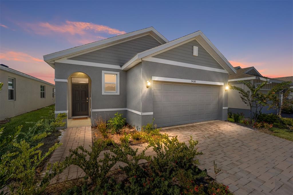 A single-story house with gray siding, a two-car garage, and a paved driveway at dusk — 5430 NW 46TH LANE ROAD, OCALA, FL