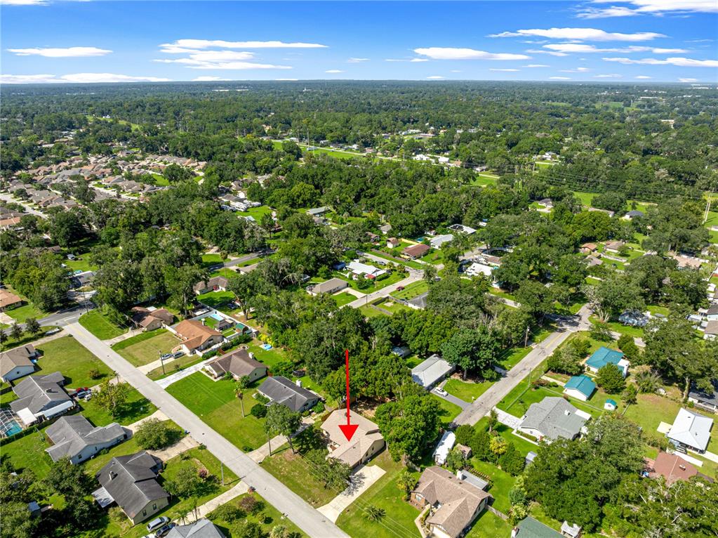An aerial view shows a single-story house with a red arrow pointing to its roof — 804 NE 46TH COURT, OCALA, FL