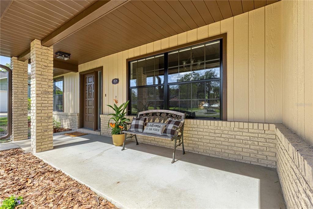 A covered front porch features a brick pillar, a bench, and a front door — 804 NE 46TH COURT, OCALA, FL