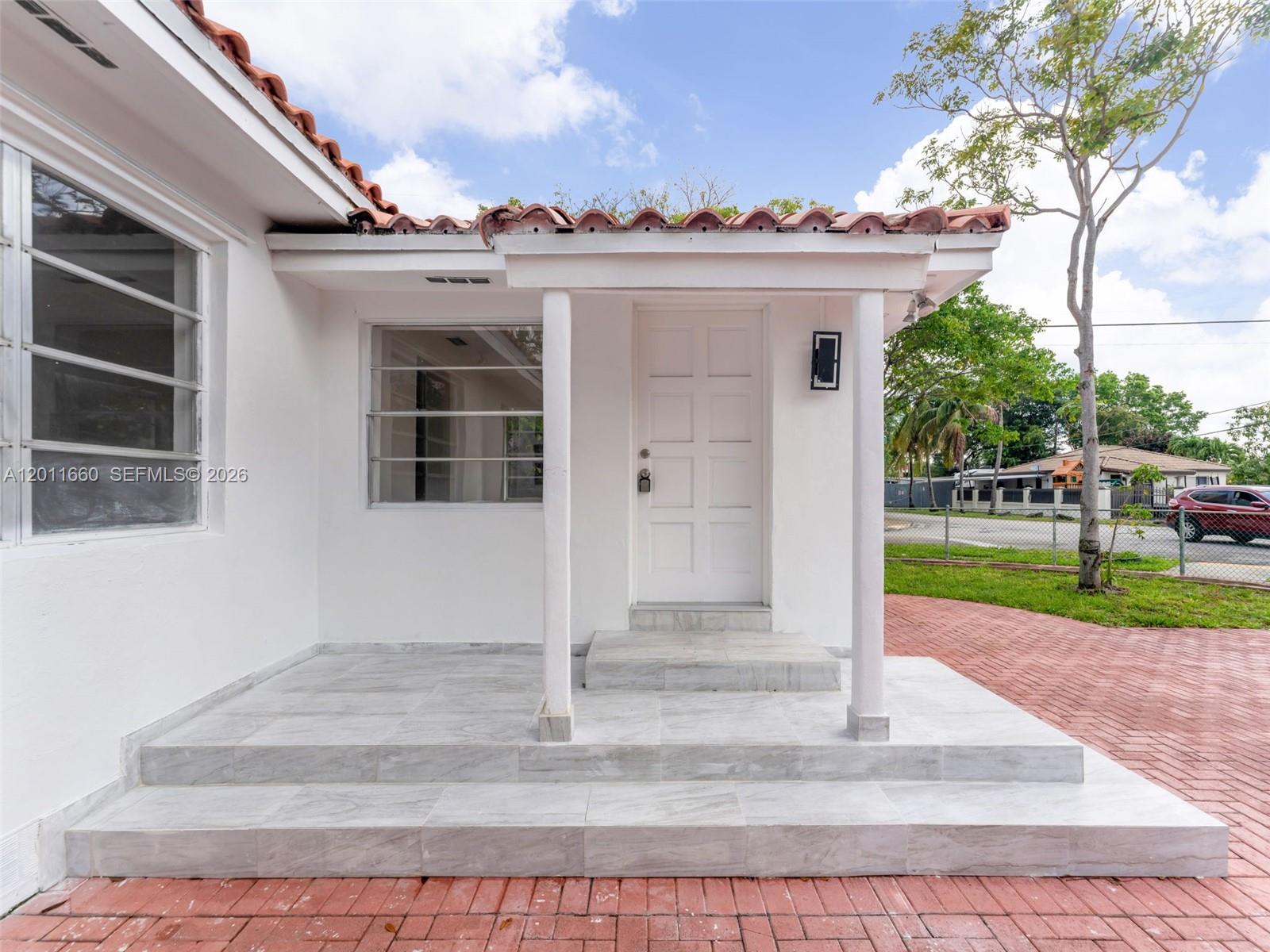 A white house exterior features a tiled porch, two support columns, and a front door — 520 NW 32nd Pl # 520, Miami FL 33125, MIAMI, FL