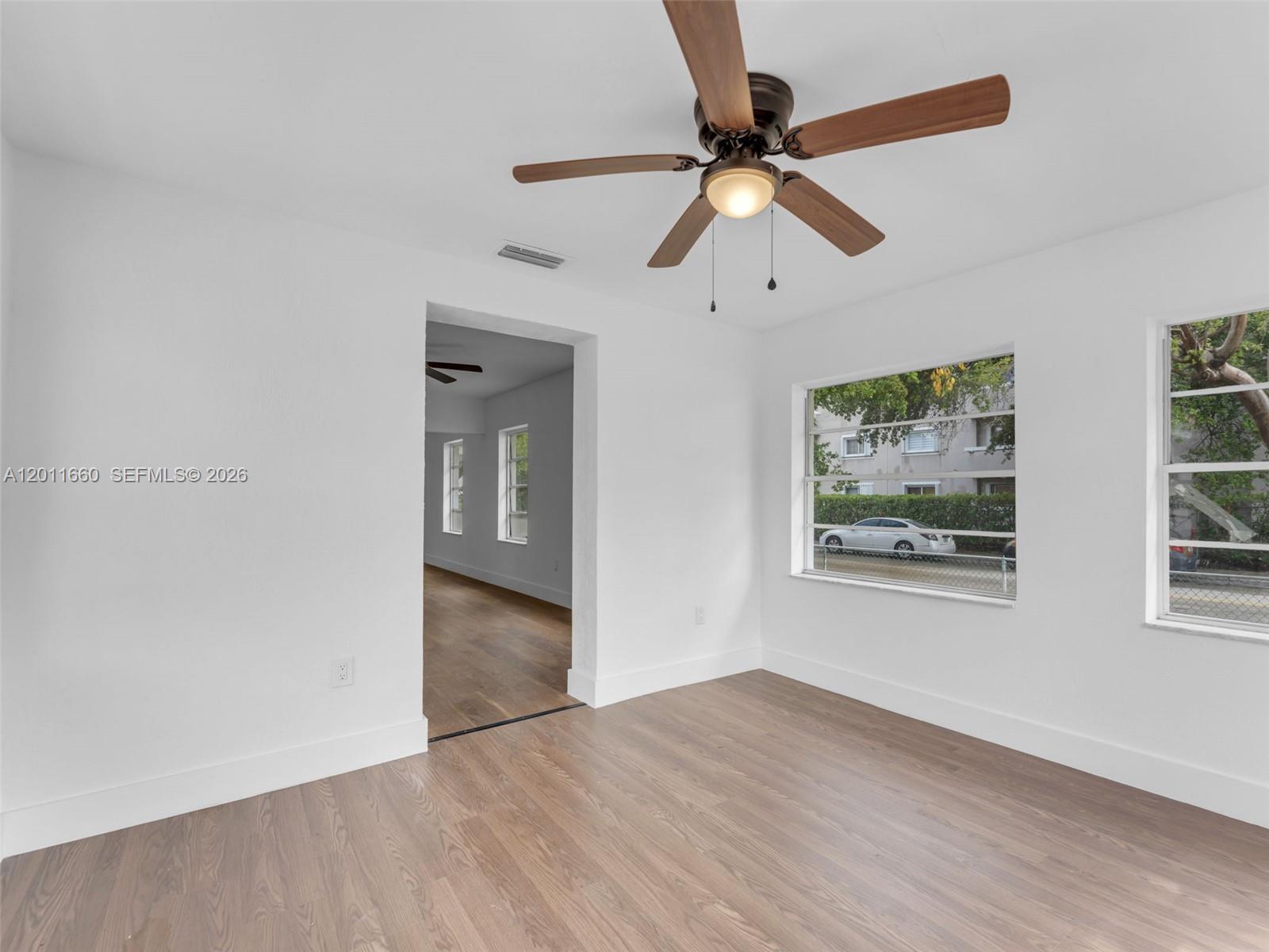 A bright room features white walls, wood-look flooring, a ceiling fan, and two windows — 520 NW 32nd Pl # 520, Miami FL 33125, MIAMI, FL