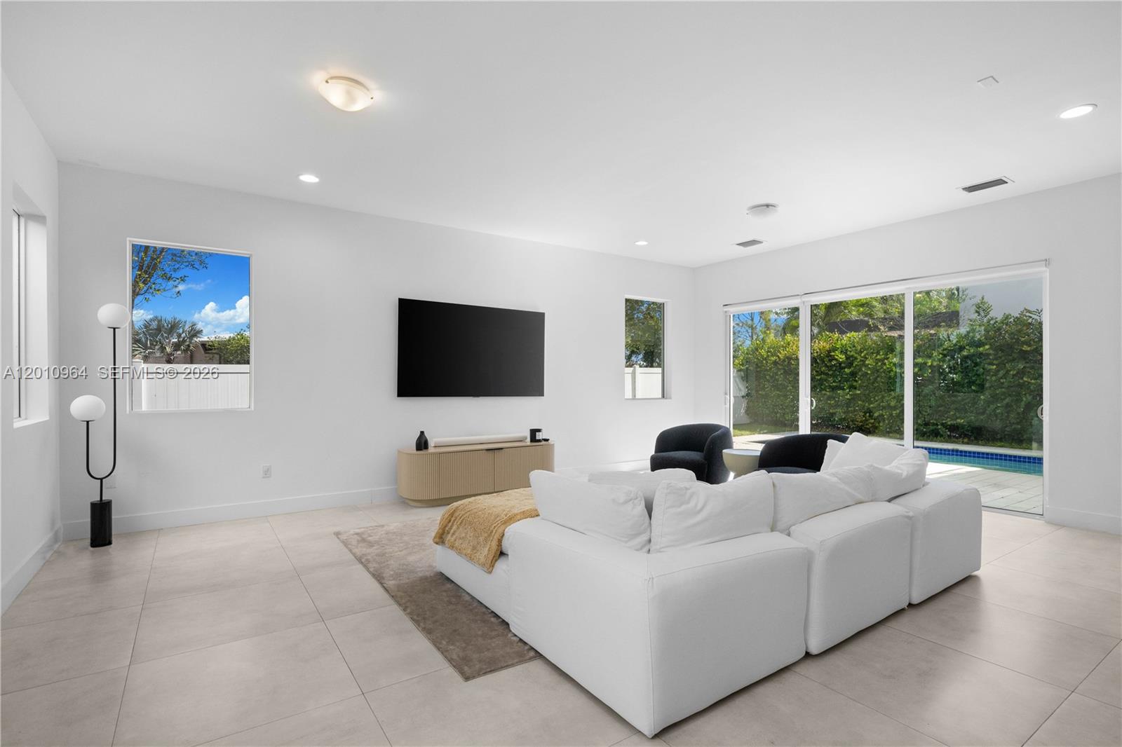 A bright living room features white walls, tile floors, a sectional sofa, and sliding glass doors — 9915 NW 75th St # 9915, Doral FL 33178, DORAL, FL