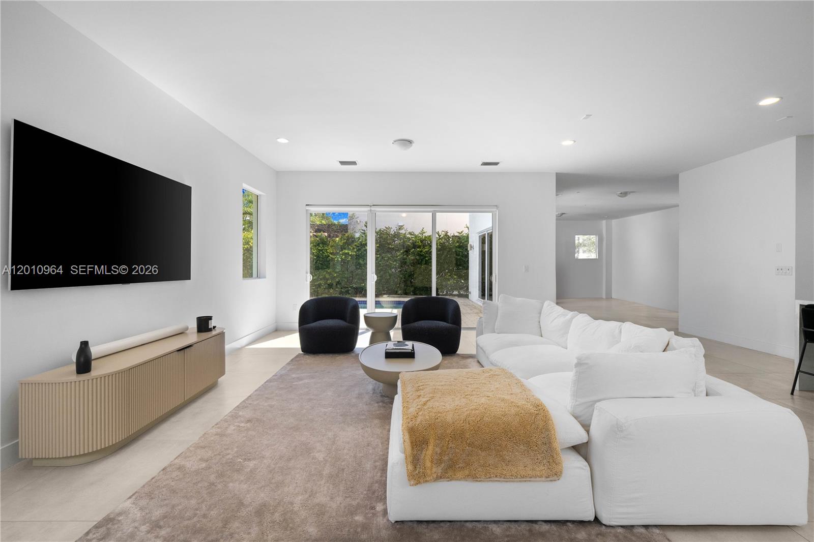 A modern living room features a white sectional sofa, two black chairs, and a television — 9915 NW 75th St # 9915, Doral FL 33178, DORAL, FL