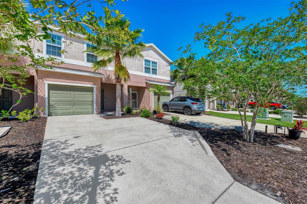 A two-story townhouse with a green garage door, a concrete driveway, and a palm tree — 4745 VIGNETTE WAY, SARASOTA, FL