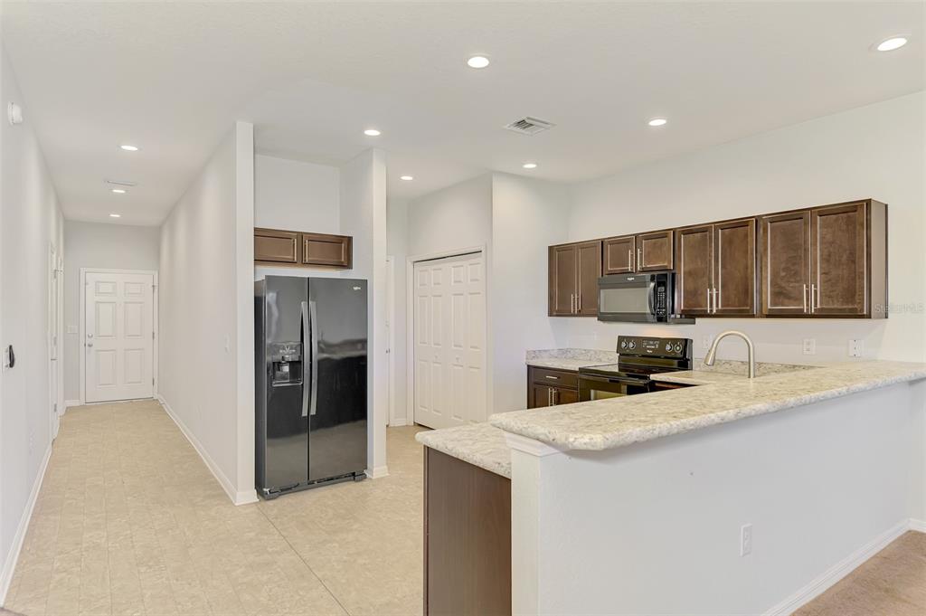 A kitchen features dark wood cabinets, granite countertops, a black refrigerator, and a breakfast bar — 4745 VIGNETTE WAY, SARASOTA, FL