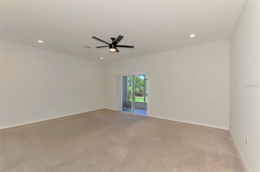 An empty bedroom with beige carpet, white walls, a ceiling fan, and a sliding glass door — 4745 VIGNETTE WAY, SARASOTA, FL