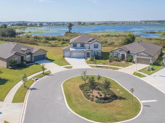 An aerial view shows three suburban houses situated around a circular cul-de-sac near a lake — 9503 IBIS GROVE BOULEVARD, WESLEY CHAPEL, FL