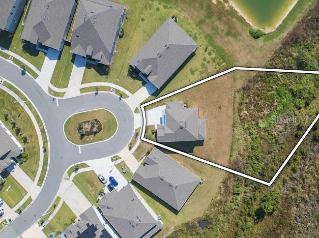 This aerial view shows a residential house on a corner lot in a suburban neighborhood — 9503 IBIS GROVE BOULEVARD, WESLEY CHAPEL, FL