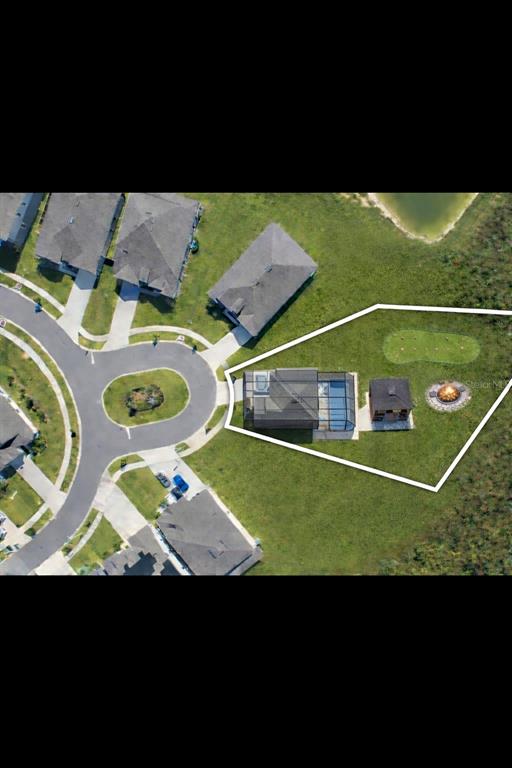 An aerial view shows a house with a pool enclosure, gazebo, and fire pit — 9503 IBIS GROVE BOULEVARD, WESLEY CHAPEL, FL