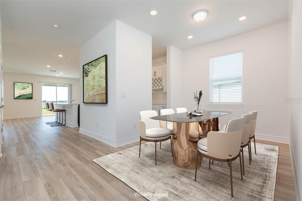 A dining area with a glass table and chairs sits next to a kitchen island — 9503 IBIS GROVE BOULEVARD, WESLEY CHAPEL, FL