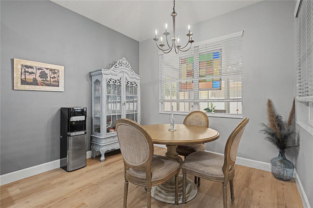 A dining room with gray walls, a round wooden table, and a stained glass window — 34726 PINEHURST GREENE WAY, ZEPHYRHILLS, FL