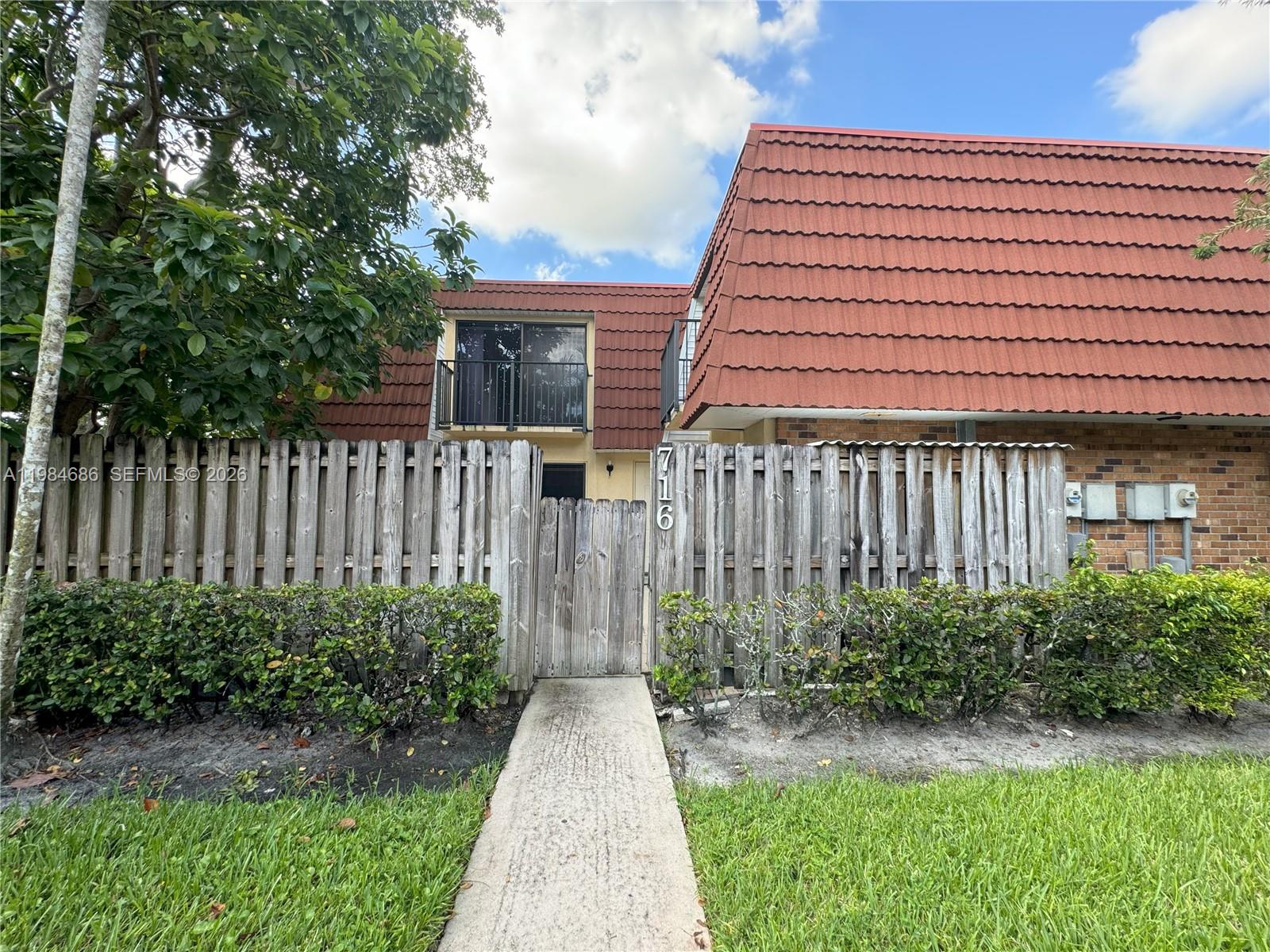 A wooden fence with a gate leads to the entrance of a two-story building — 716 NW 98th Way, Plantation FL 33324, PLANTATION, FL