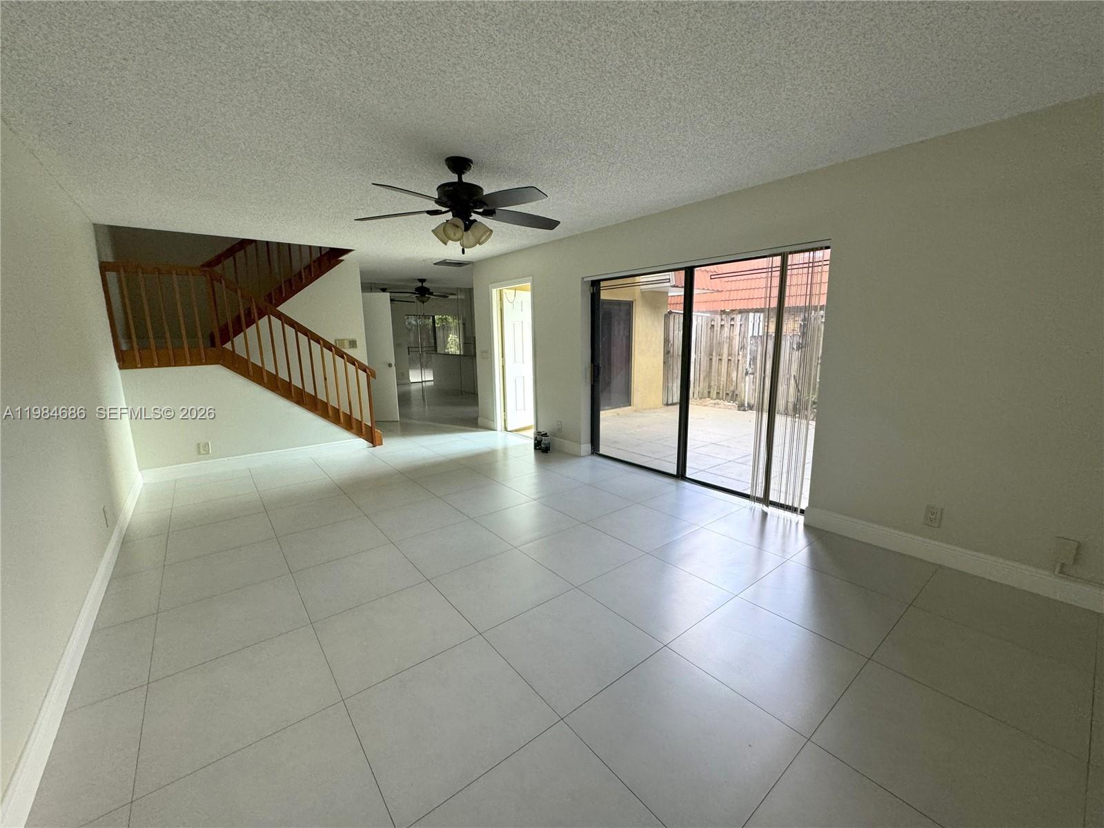 A living room features large light-colored floor tiles, a ceiling fan, and sliding glass doors — 716 NW 98th Way, Plantation FL 33324, PLANTATION, FL