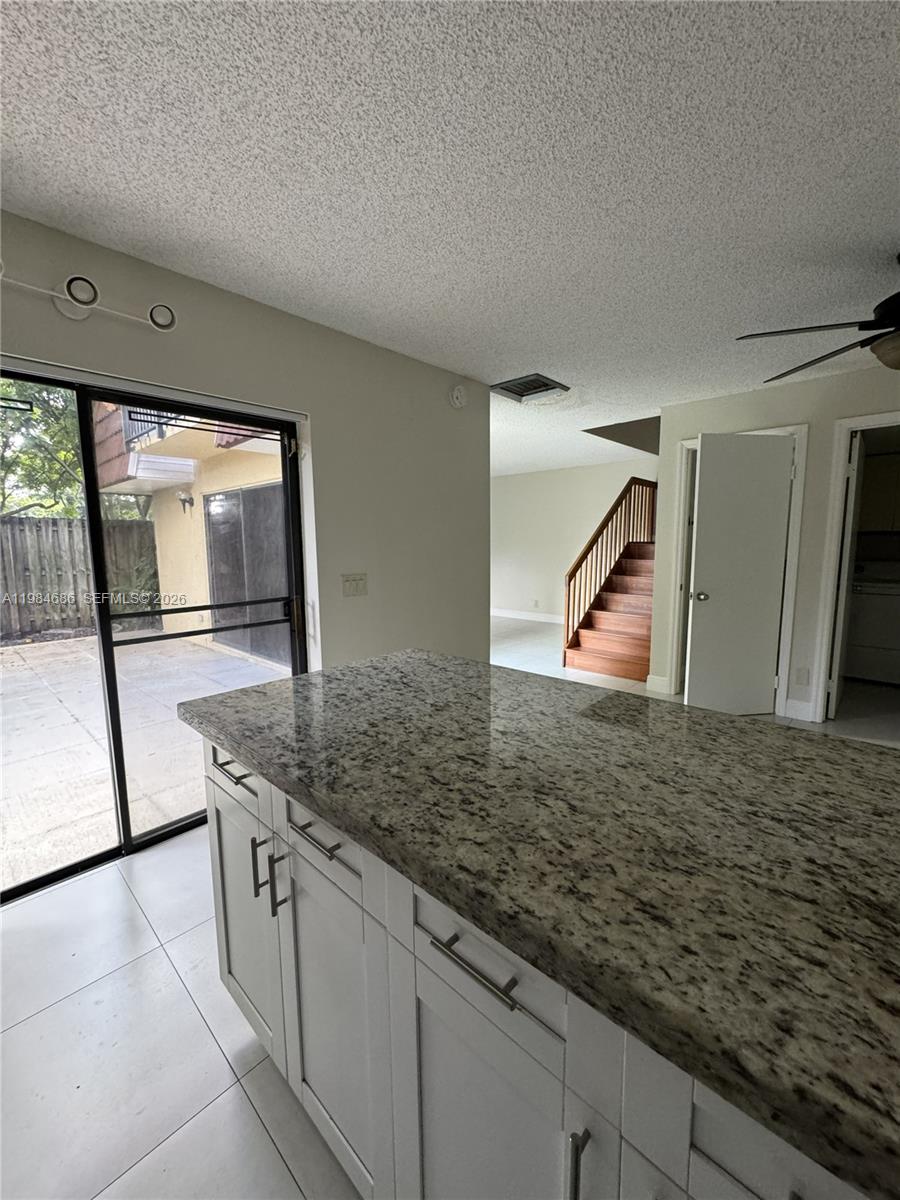 A kitchen island with granite countertops overlooks a patio through a sliding glass door — 716 NW 98th Way, Plantation FL 33324, PLANTATION, FL