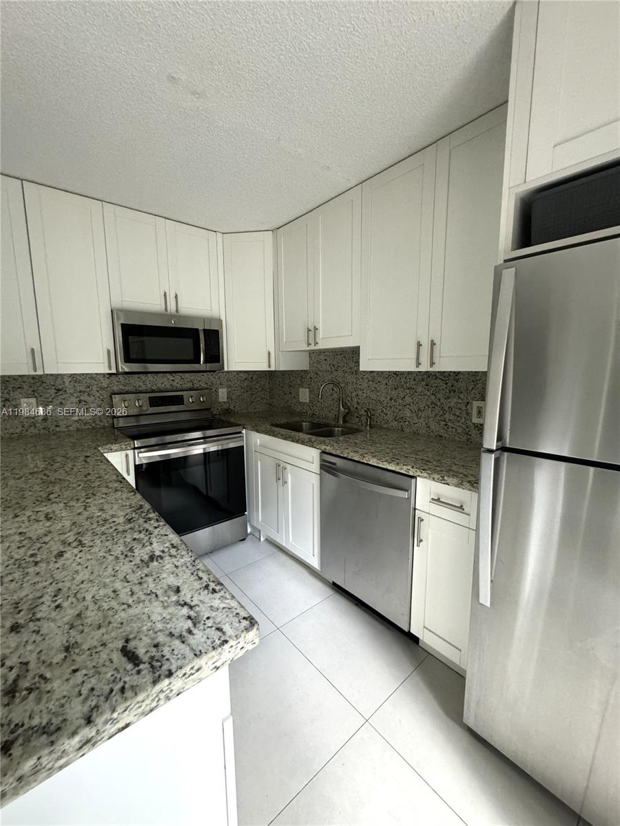 A kitchen features white cabinets, granite countertops, stainless steel appliances, and light-colored tile flooring — 716 NW 98th Way, Plantation FL 33324, PLANTATION, FL