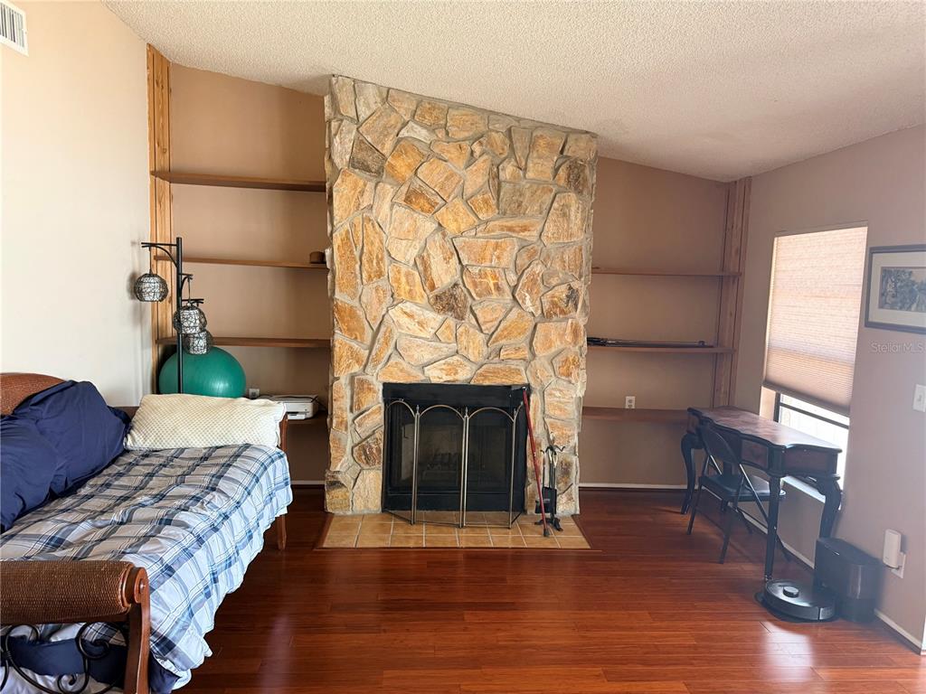 A living room features a stone fireplace, built-in wooden shelves, and hardwood flooring — 2034 MONTEGO COURT, OLDSMAR, FL
