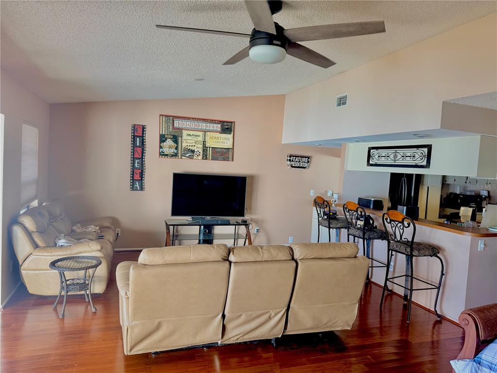 A living room features a tan leather sofa, a television, and a breakfast bar — 2034 MONTEGO COURT, OLDSMAR, FL