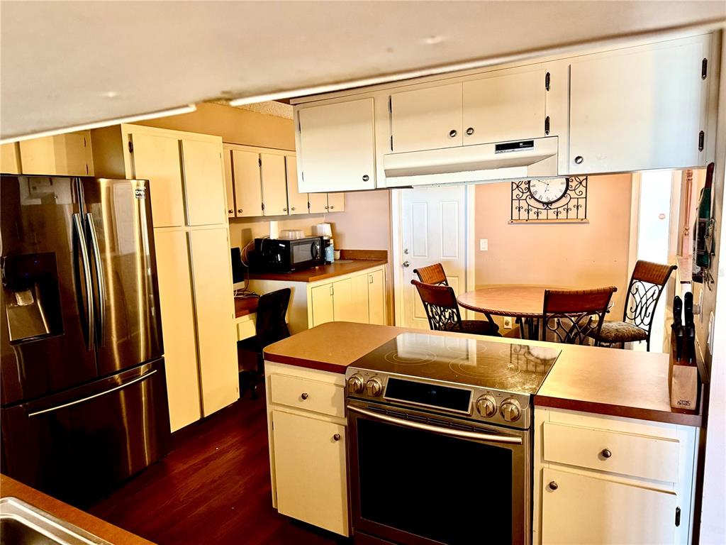 A kitchen features white cabinets, stainless steel appliances, and a dining area with a table — 2034 MONTEGO COURT, OLDSMAR, FL