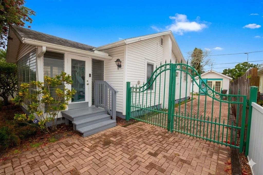 A white house with a screened porch, gray steps, and a green metal gate — 2907 CLINTON STREET S, GULFPORT, FL