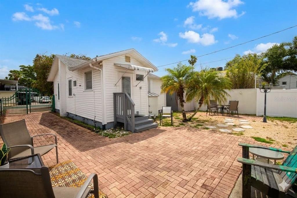 A small white house with a brick patio and a fenced backyard under a blue sky — 2907 CLINTON STREET S, GULFPORT, FL