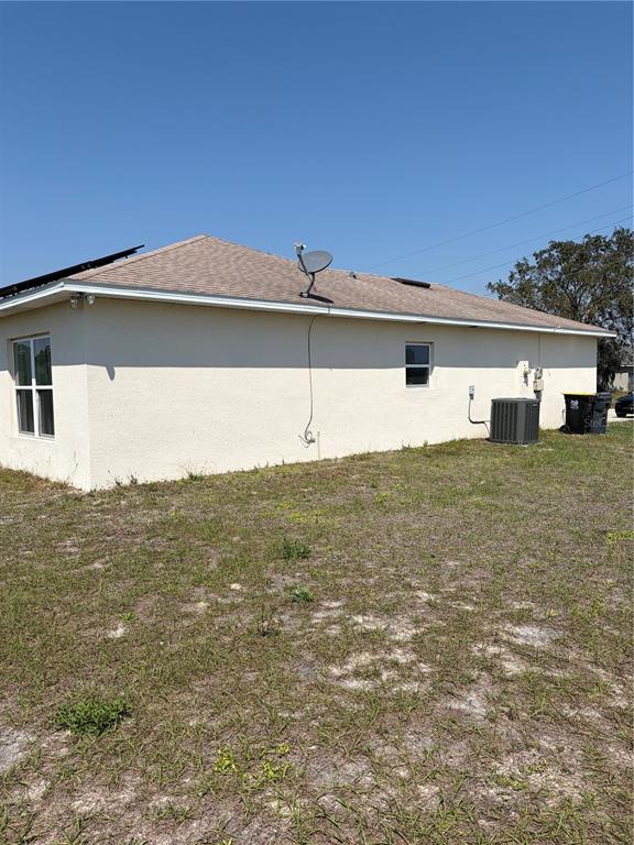 The exterior side of a beige stucco house features a satellite dish and HVAC unit — 1939 MANATEE DRIVE, KISSIMMEE, FL