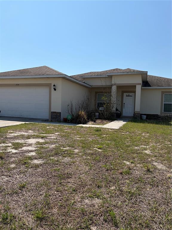 A single-story house with a beige stucco exterior, a two-car garage, and a front yard — 1939 MANATEE DRIVE, KISSIMMEE, FL