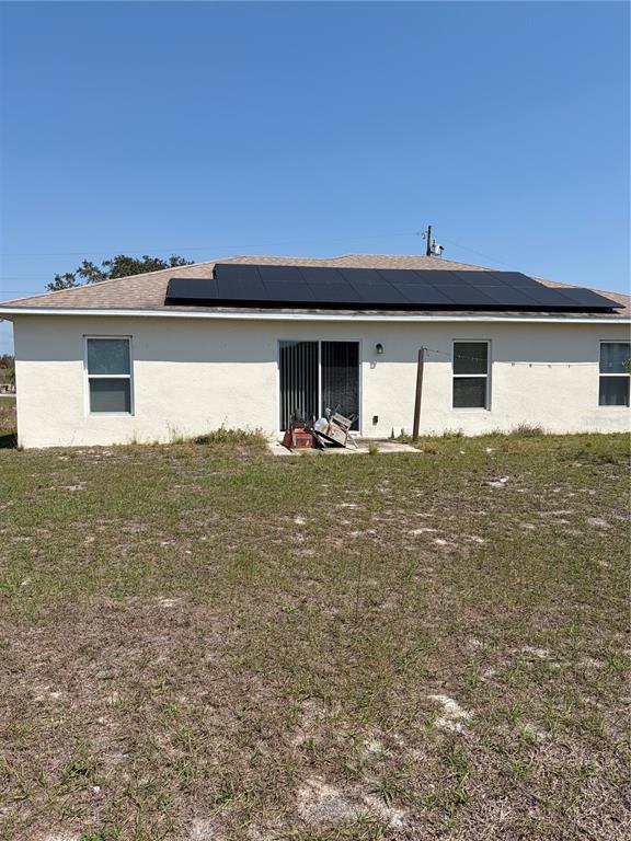 The rear exterior of a single-story house features a solar panel array on the roof — 1939 MANATEE DRIVE, KISSIMMEE, FL
