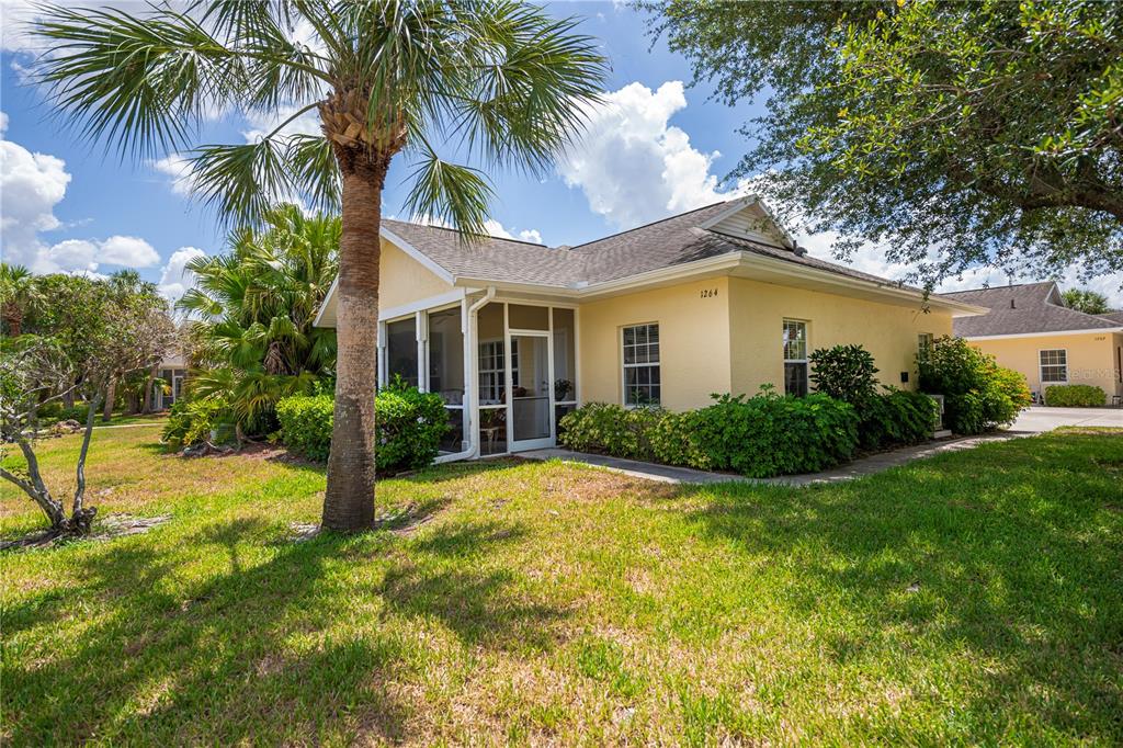 A yellow single-story house features a screened-in porch, a palm tree, and green landscaping — 1264 RED OAK LANE, PORT CHARLOTTE, FL
