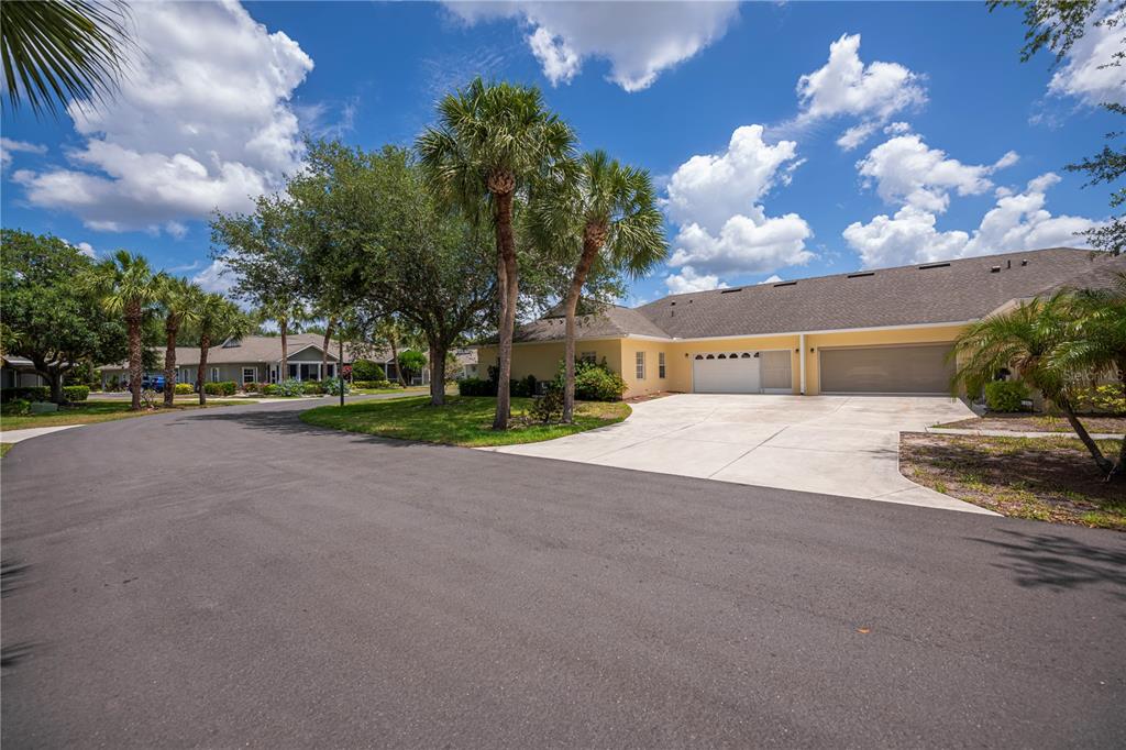 A yellow single-story house with a two-car garage and palm trees under a blue sky — 1264 RED OAK LANE, PORT CHARLOTTE, FL