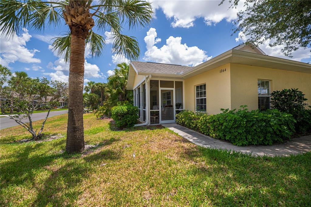 A yellow house with a screened-in porch and a palm tree in the front yard — 1264 RED OAK LANE, PORT CHARLOTTE, FL
