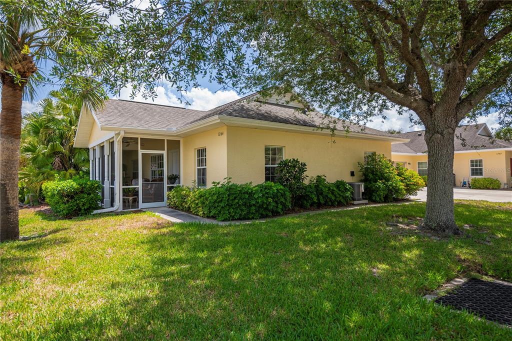 A yellow single-story house features a screened-in porch and a large tree in the yard — 1264 RED OAK LANE, PORT CHARLOTTE, FL