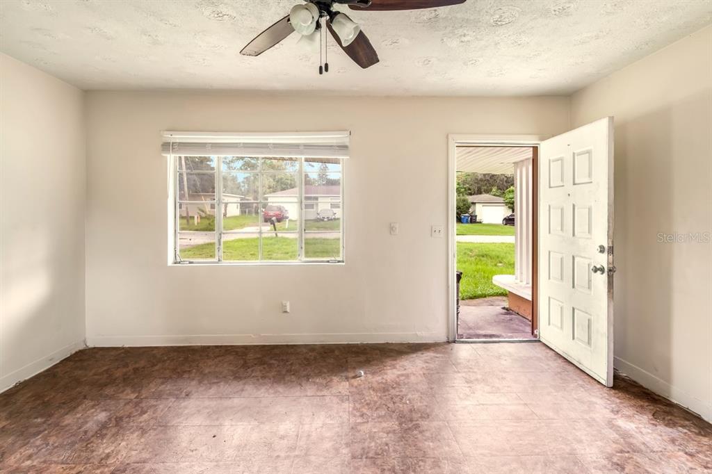 An empty room with white walls, a ceiling fan, and dark mottled flooring — 1329 WOODBINE STREET, CLEARWATER, FL