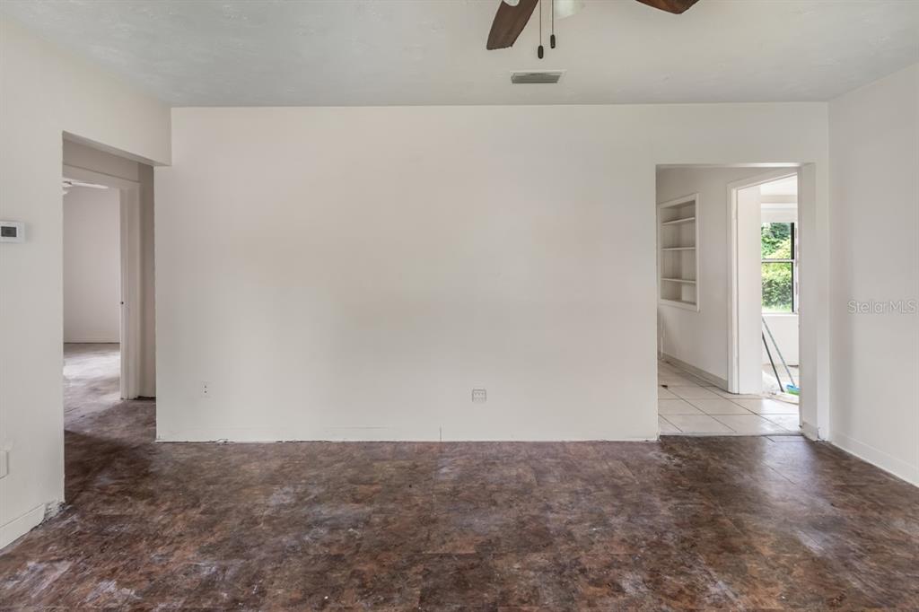 An empty room features a ceiling fan, a white door, and dark vinyl flooring — 1329 WOODBINE STREET, CLEARWATER, FL