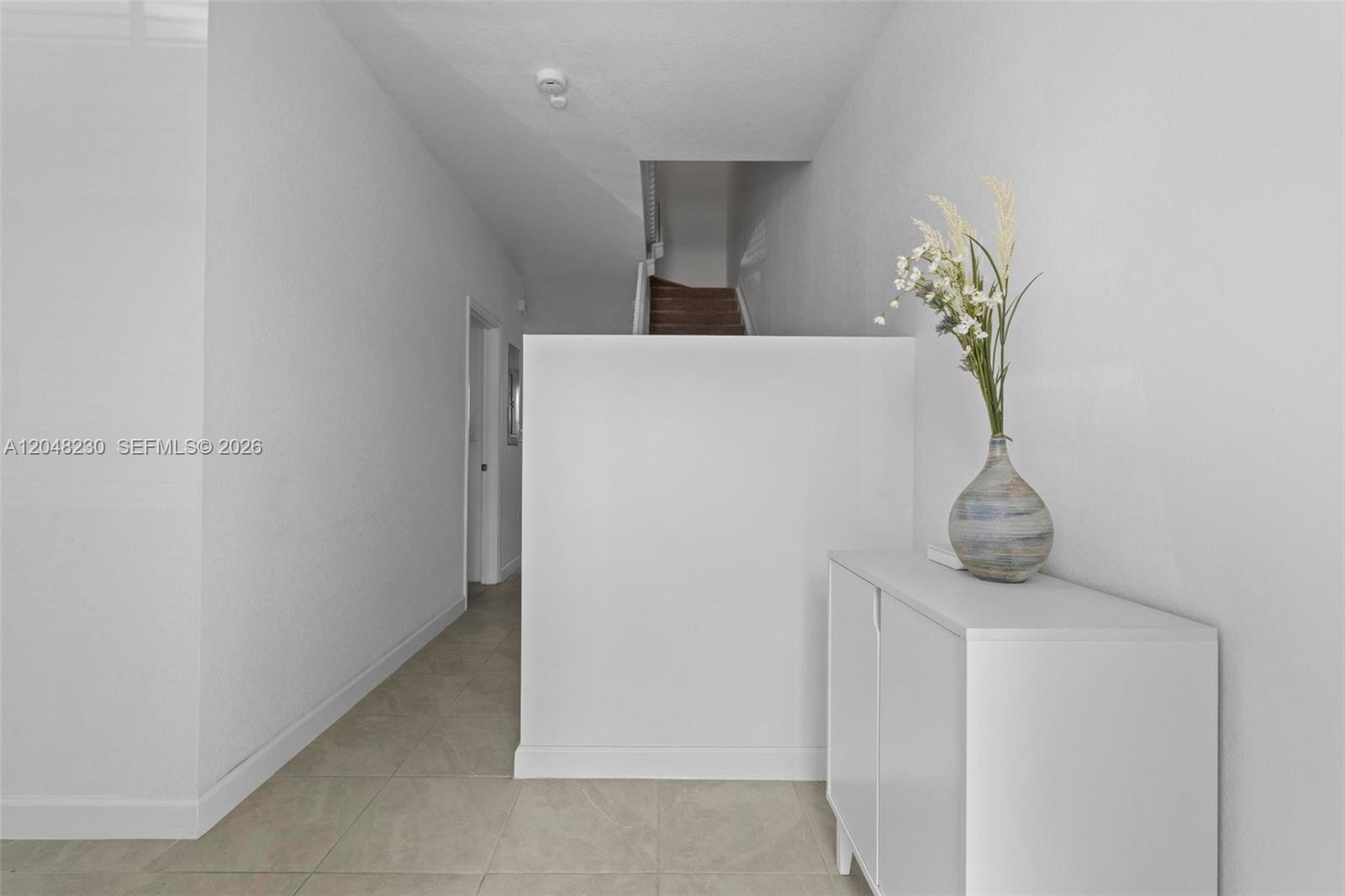 A white hallway features a low partition wall, a small cabinet, and a staircase — 12204 NW 23rd Ct, Miami FL 33167, MIAMI, FL