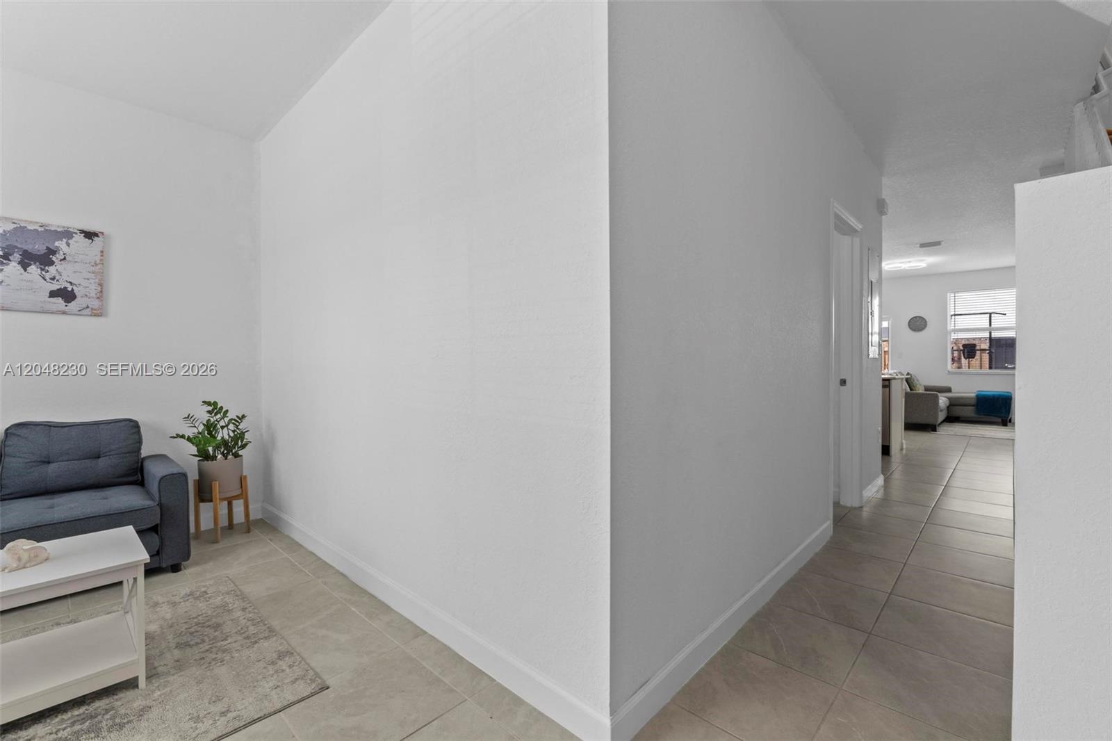 A white-walled hallway leads from a small seating area toward a living room — 12204 NW 23rd Ct, Miami FL 33167, MIAMI, FL