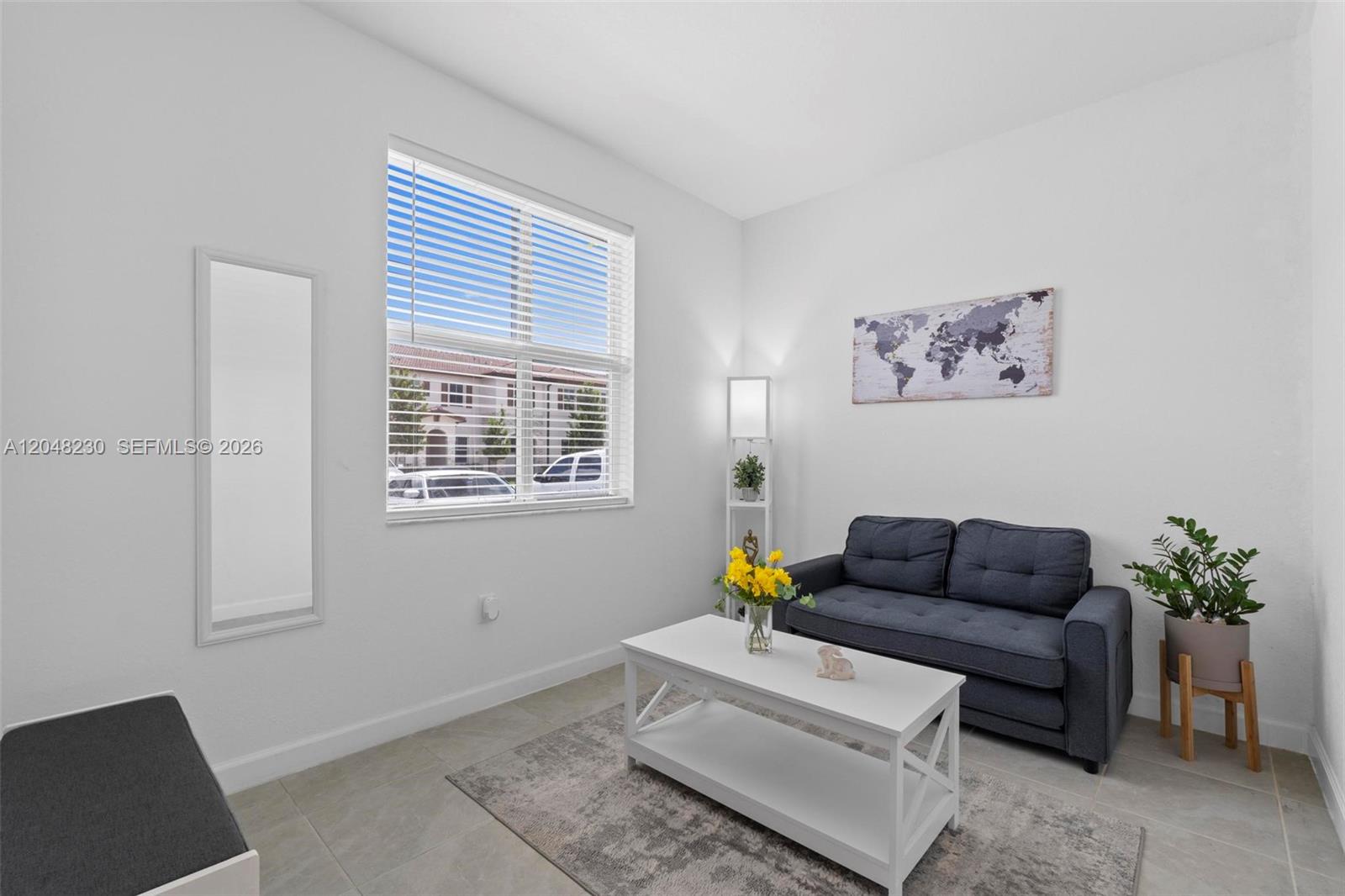 A living room features a dark sofa, white coffee table, area rug, and wall art — 12204 NW 23rd Ct, Miami FL 33167, MIAMI, FL