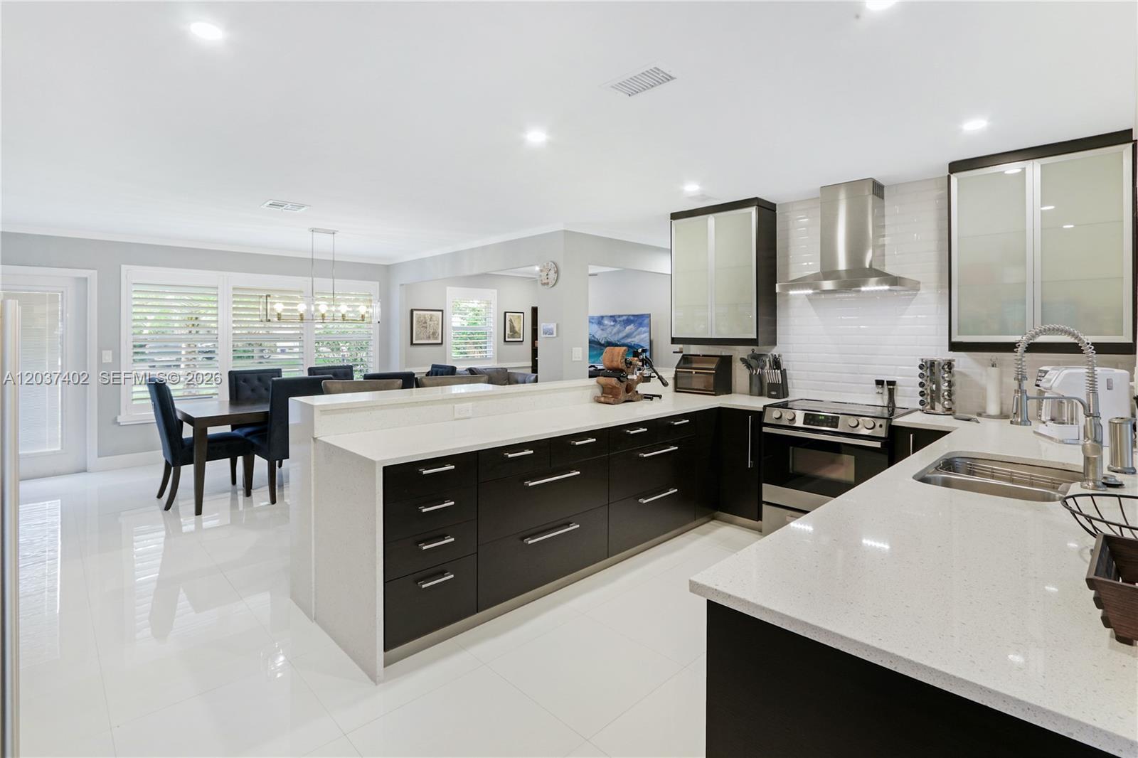 A modern kitchen features dark cabinetry, white quartz countertops, and a large central island — 424 NE 27th Dr, Wilton Manors FL 33334, WILTON MANORS, FL