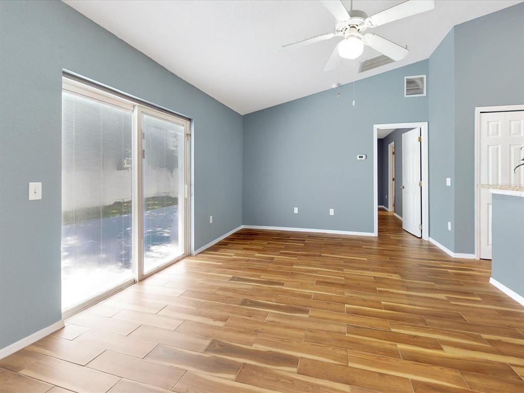 An empty room with blue walls, wood-look tile flooring, a ceiling fan, and sliding doors — 1444 SWIFT COURT, POINCIANA, FL