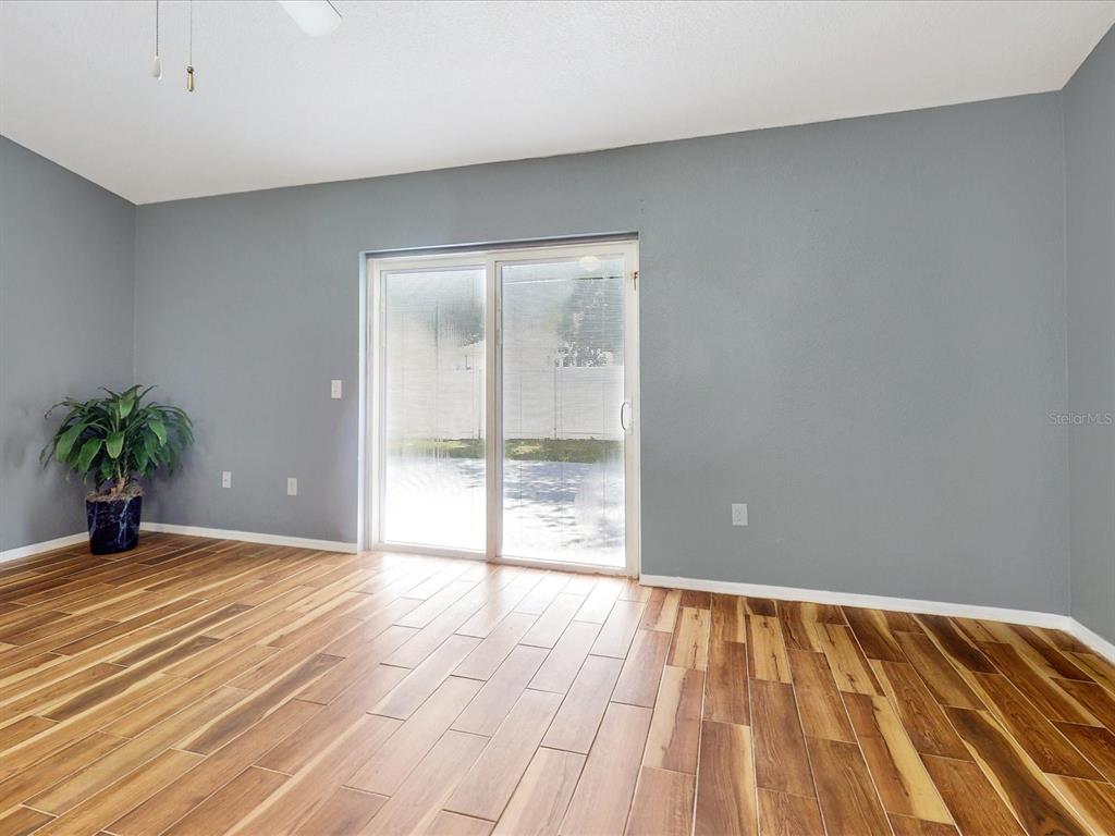 A room with gray walls, wood-look tile flooring, and a sliding glass door to the backyard — 1444 SWIFT COURT, POINCIANA, FL