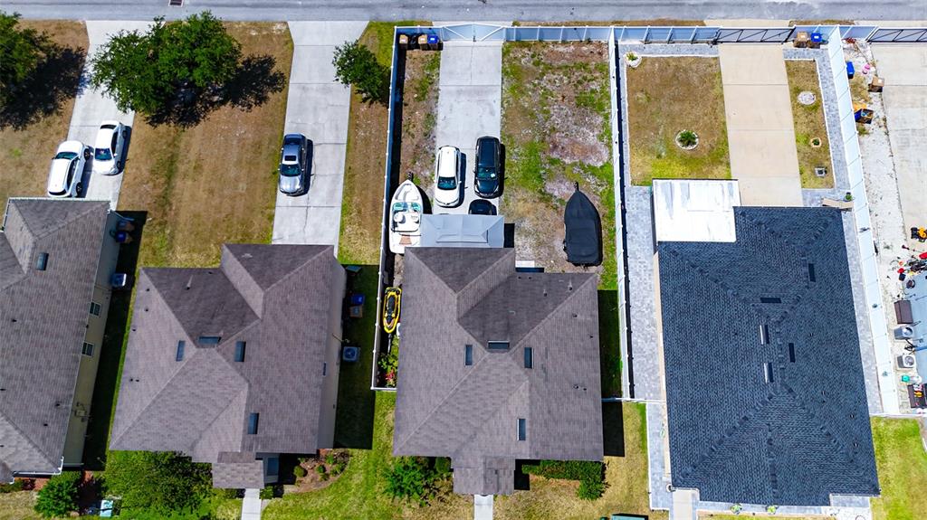 An aerial view shows three suburban houses with driveways, parked vehicles, and fenced backyards — 1957 RED CANYON DRIVE, KISSIMMEE, FL