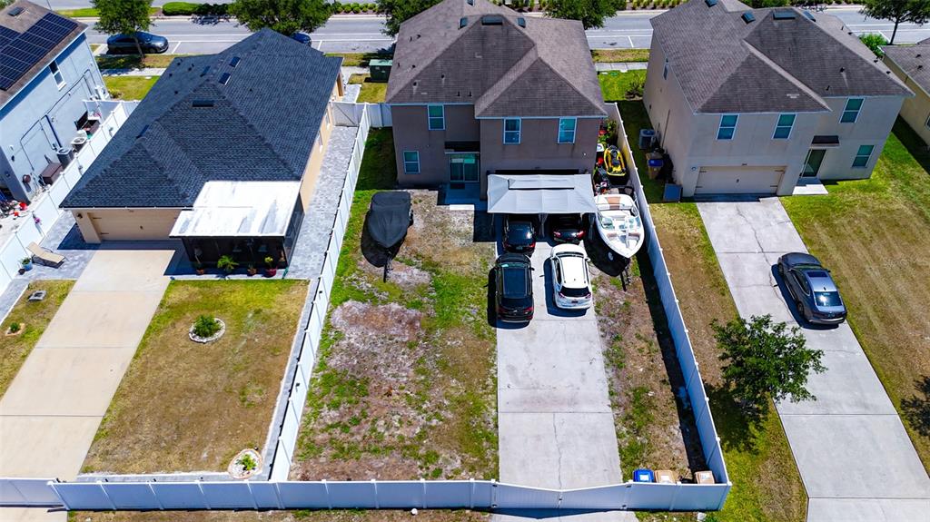An aerial view shows three suburban houses with fenced backyards and parked vehicles — 1957 RED CANYON DRIVE, KISSIMMEE, FL