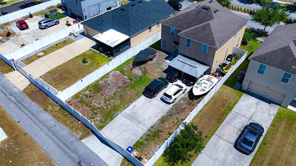 An aerial view shows a residential backyard with a concrete driveway, boat, and parked cars — 1957 RED CANYON DRIVE, KISSIMMEE, FL