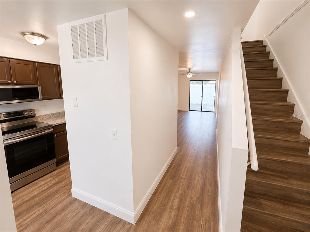 A kitchen with stainless steel appliances sits beside a staircase leading to an open living area — 202 EDEN LANE UNIT B, KISSIMMEE, FL