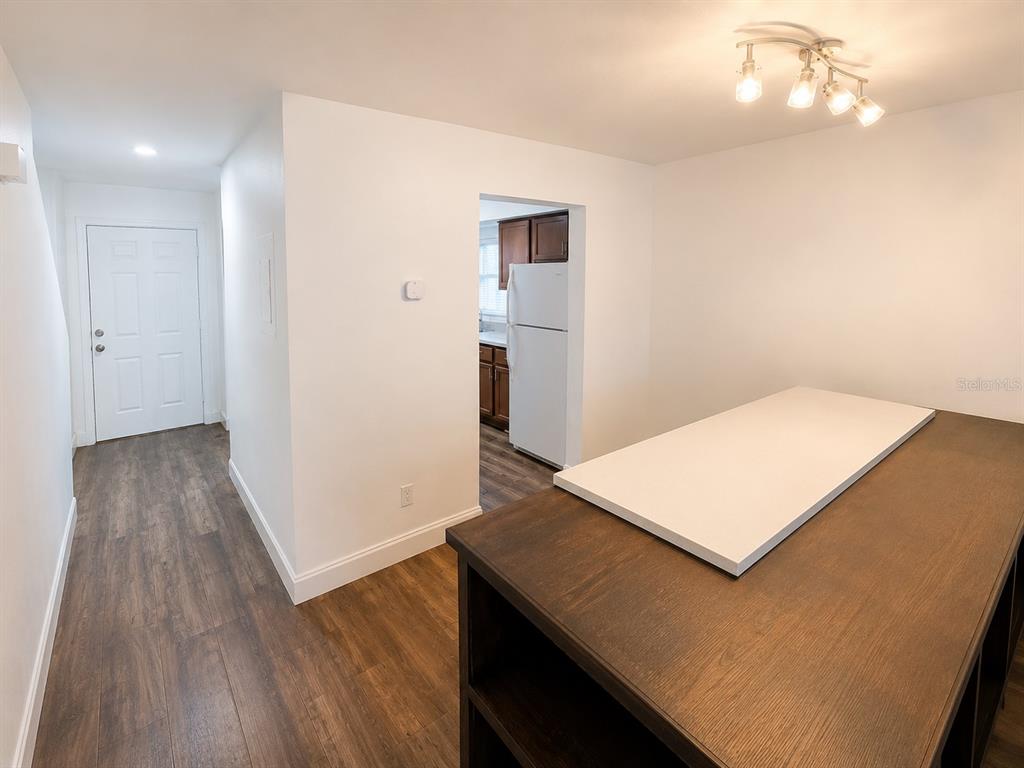 A kitchen island with a white countertop sits in a room with wood-look flooring — 202 EDEN LANE UNIT B, KISSIMMEE, FL