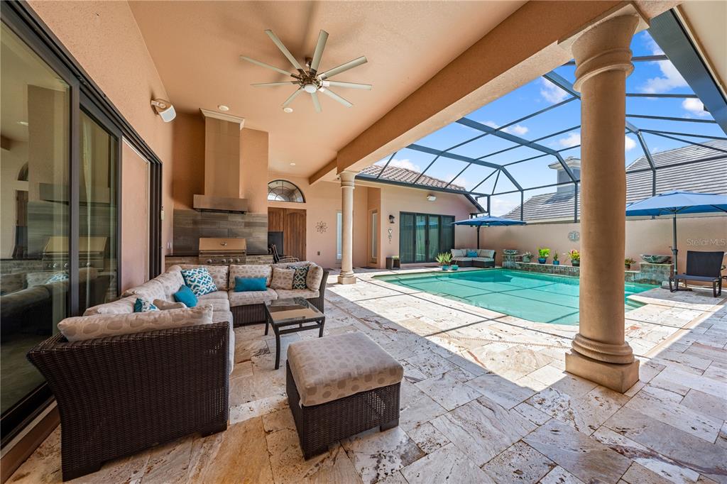 A covered patio features a sectional sofa, outdoor kitchen, and a screened-in swimming pool — 2557 HERITAGE GREEN AVENUE, DAVENPORT, FL