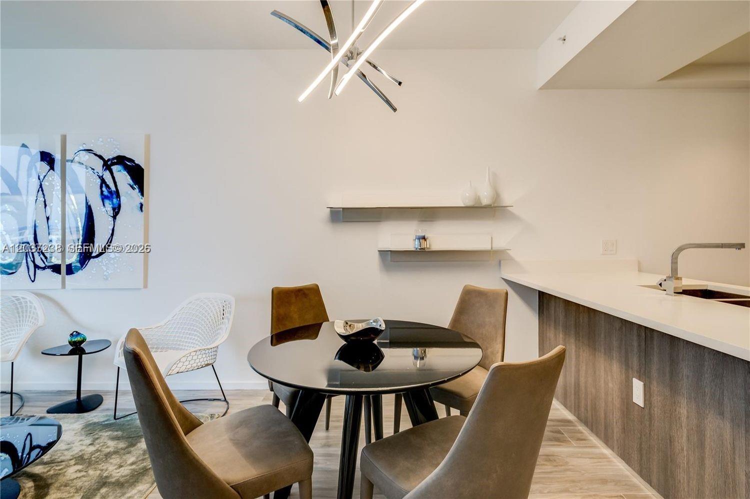 A dining area features a round black table, four chairs, and modern wall shelving — 801 S Miami Ave # 2906, Miami FL 33130, MIAMI, FL
