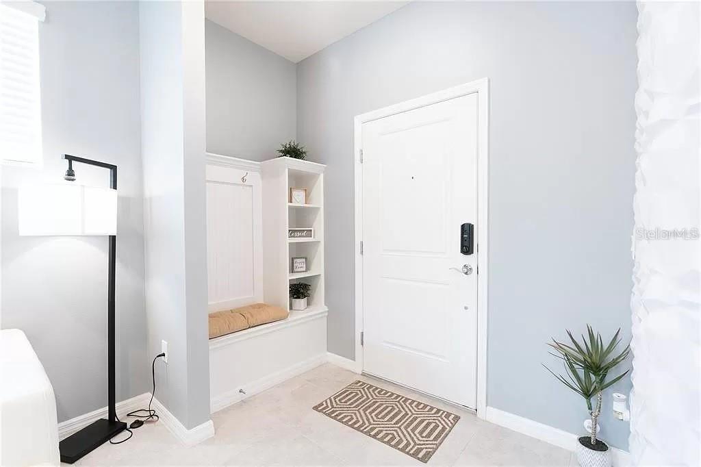 An entryway features a white built-in bench, shelving, a front door, and a floor lamp — 7243 OAKMOSS LOOP, DAVENPORT, FL